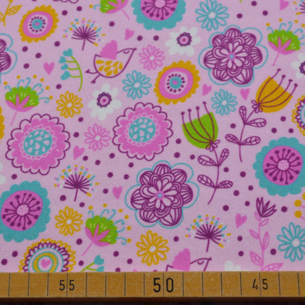 Baumwoll-Jersey in Rosa mit buntem Blumenmuster – elastischer Stoff für fröhliche Nähprojekte.